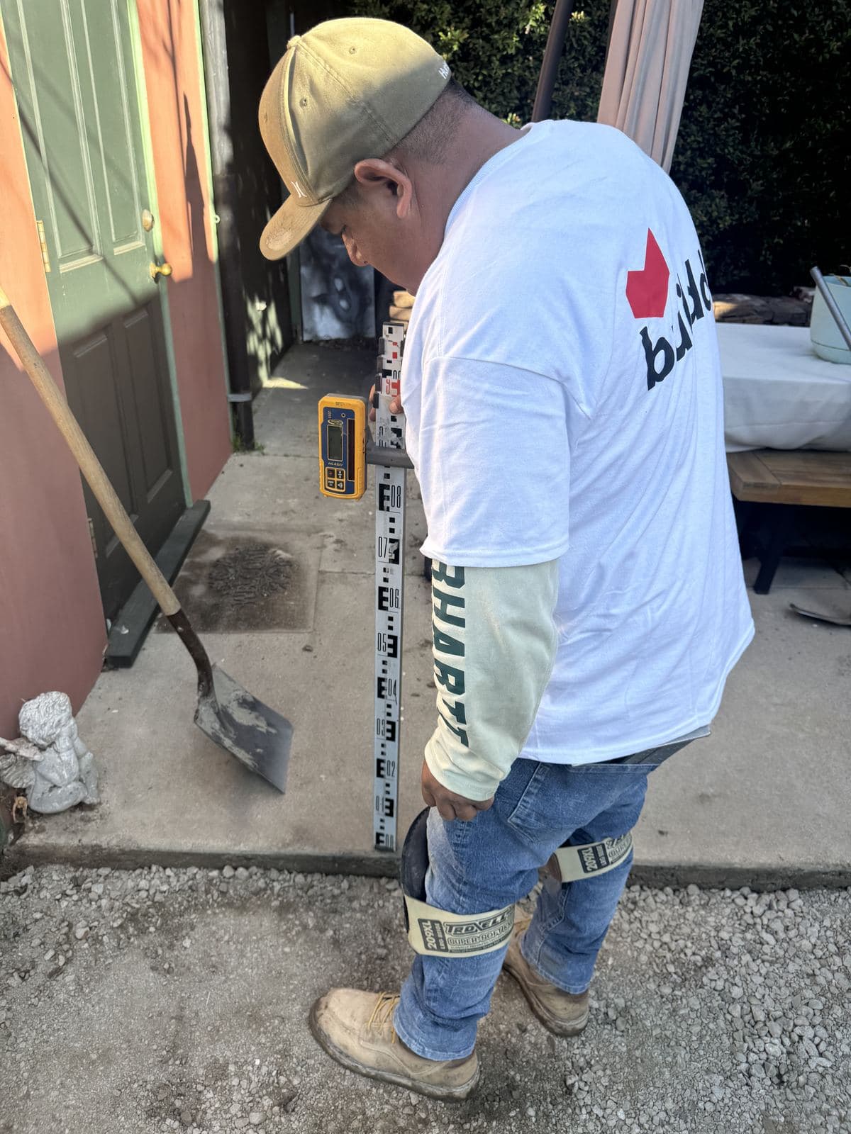 Buildda crew member raking prepared base before brick installation in Culver City backyard walkway