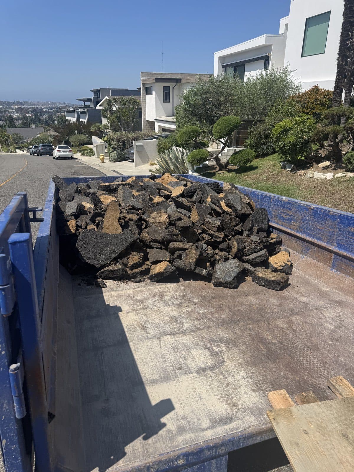 Broken asphalt loaded into a blue Culver City roll-off bin on the street