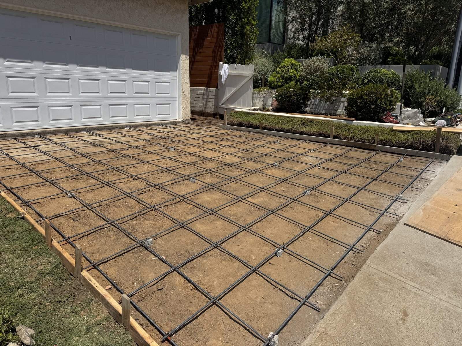 Steel grid set on the prepared driveway base in front of a garage before the concrete pour