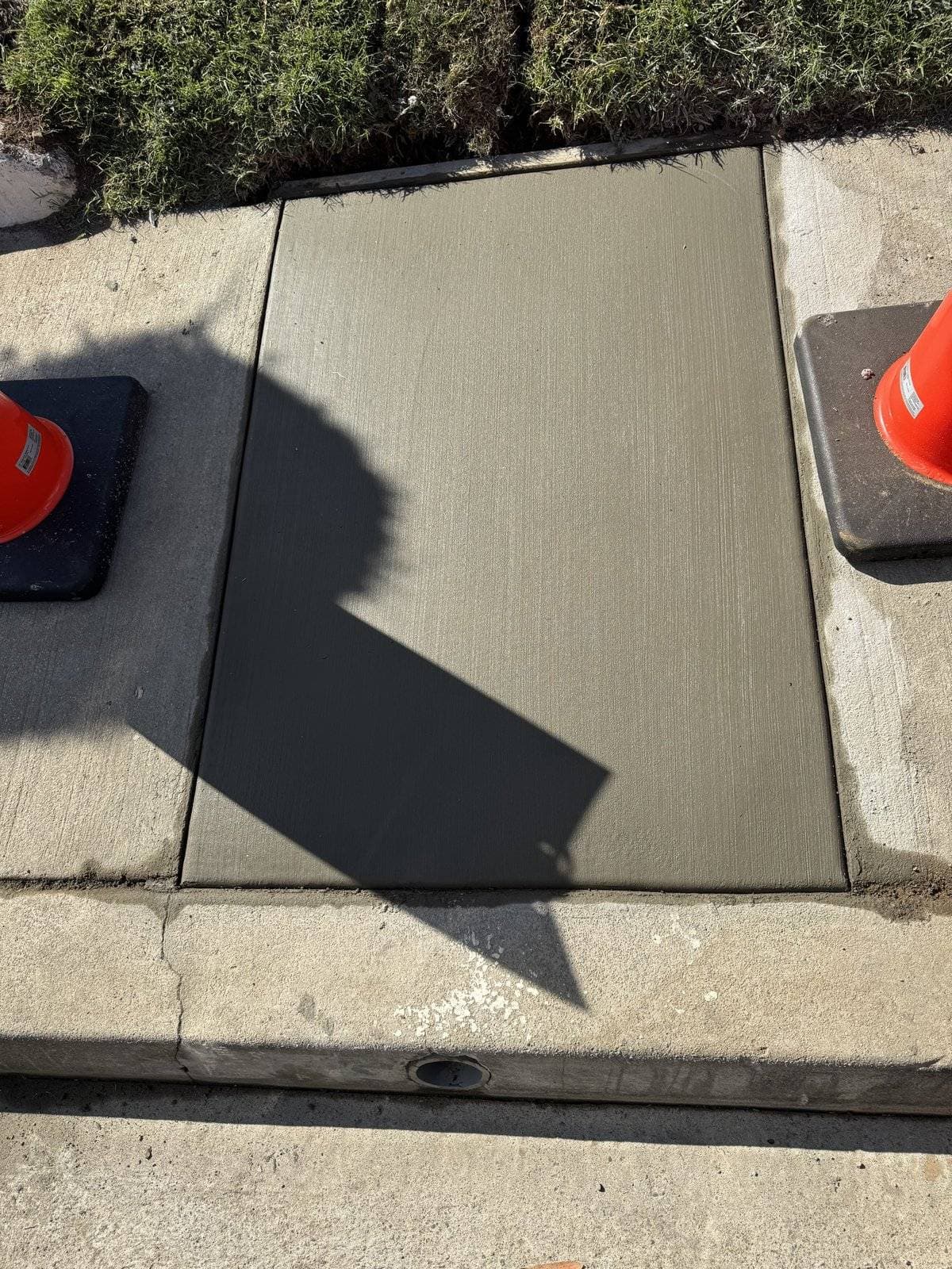 New concrete sidewalk panel at the curb above a drain outlet in Culver City