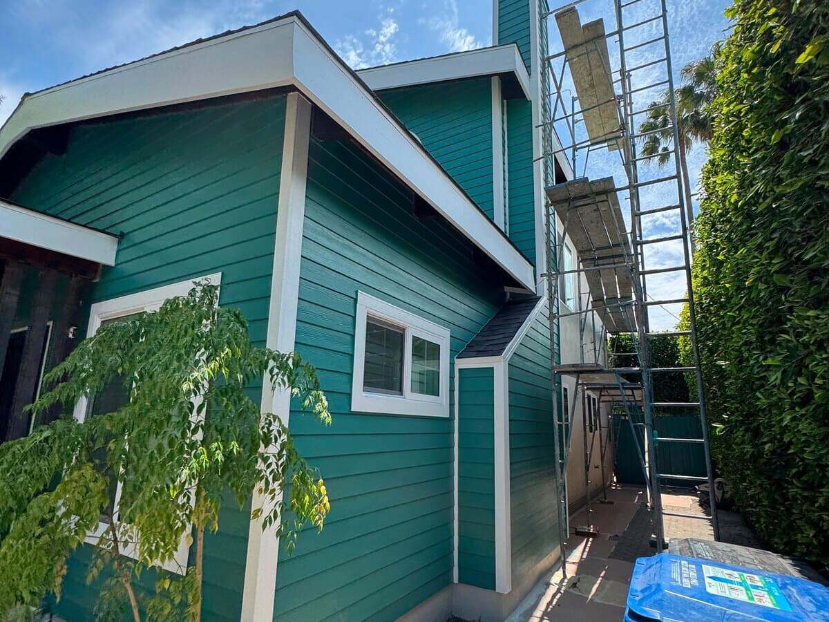 Finished James Hardie fiber-cement siding painted green with white trim on a house in Palms, Los Angeles