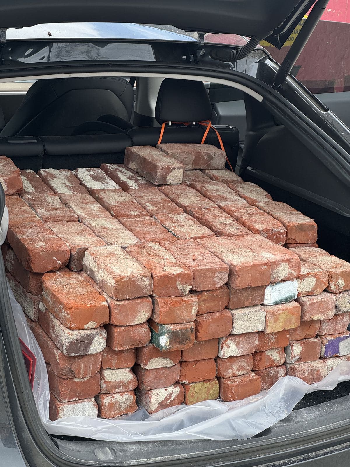 Tesla Model X trunk packed full of stacked reclaimed bricks sourced for Buildda Carlson Park project