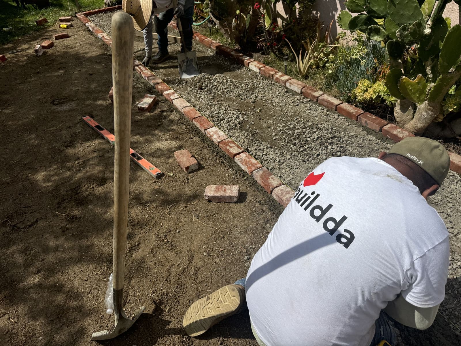Buildda crew member installing reclaimed bricks in Carlson Park backyard walkway