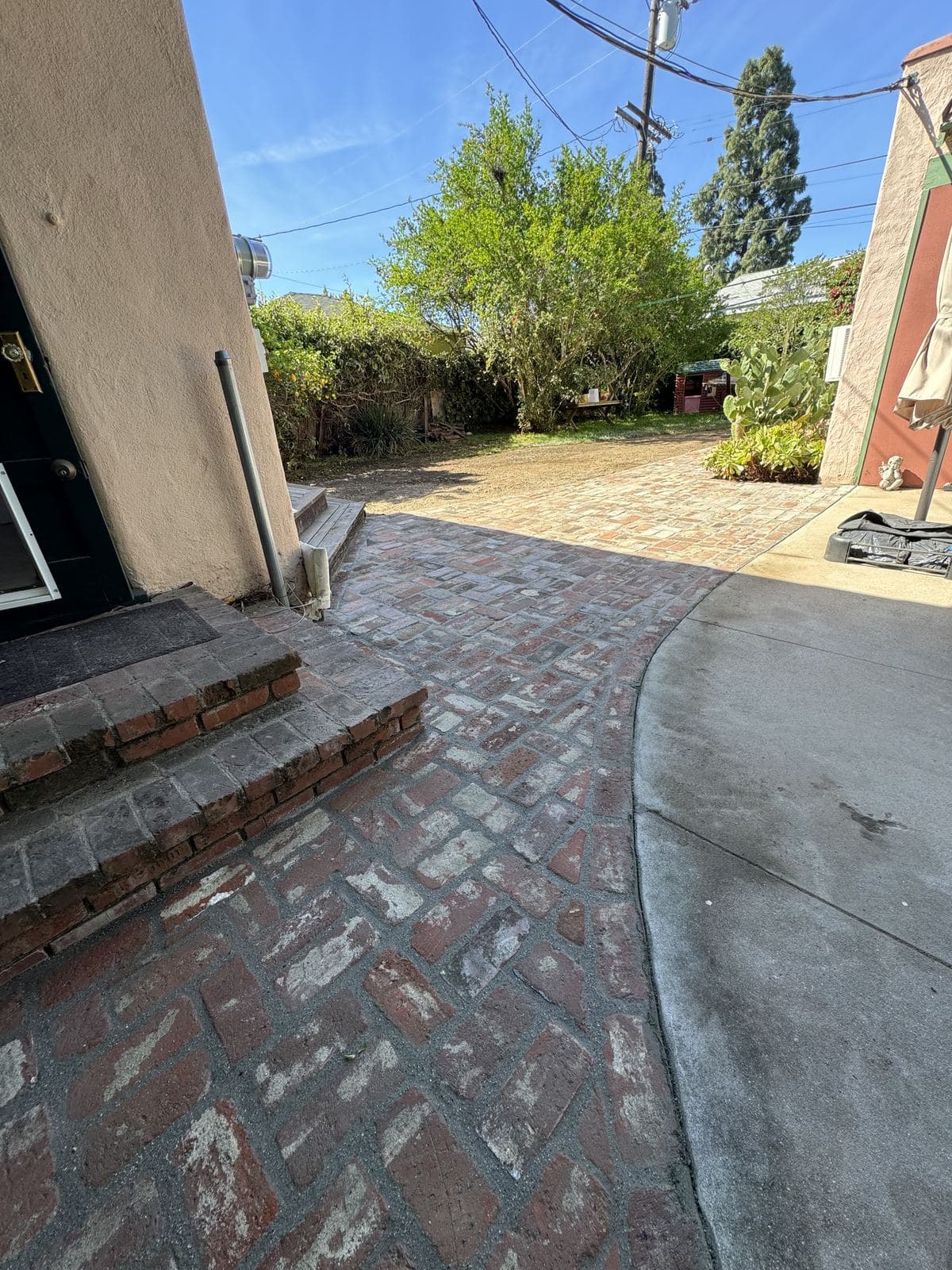 Finished reclaimed brick walkway curving through backyard to patio area with umbrella in Carlson Park Culver City