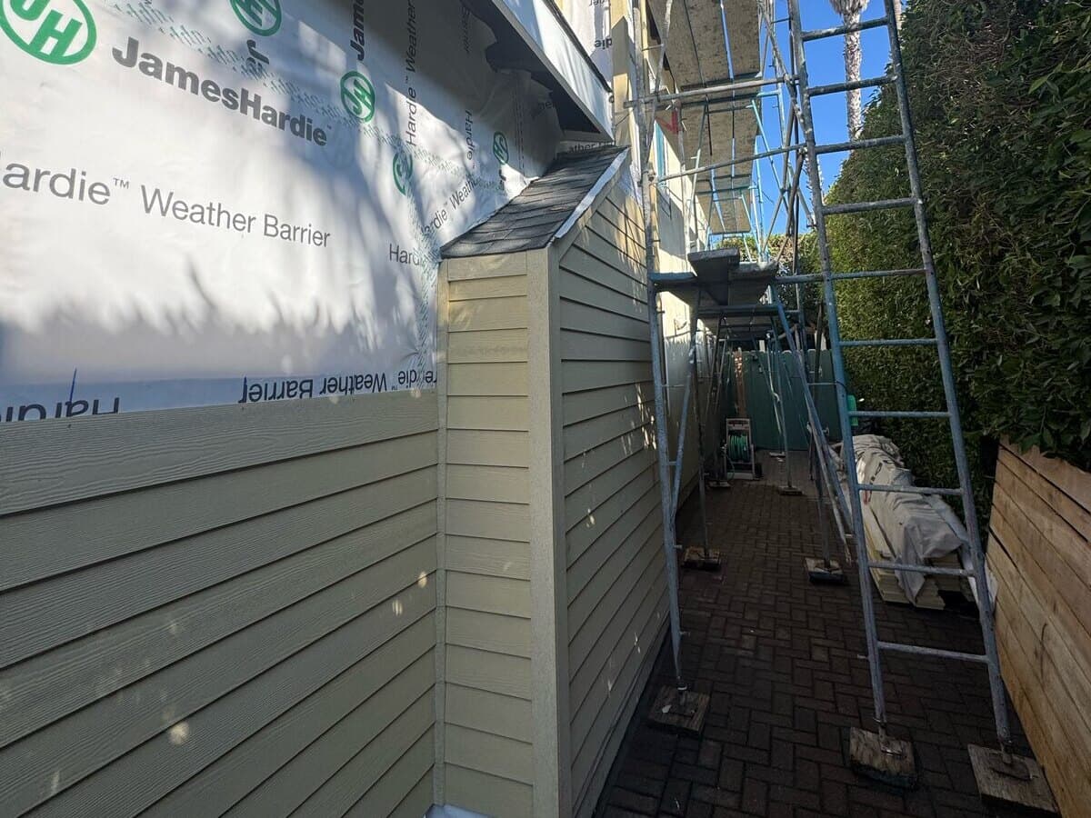 Fiber-cement lap siding being installed below the weather barrier along a side yard in Palms