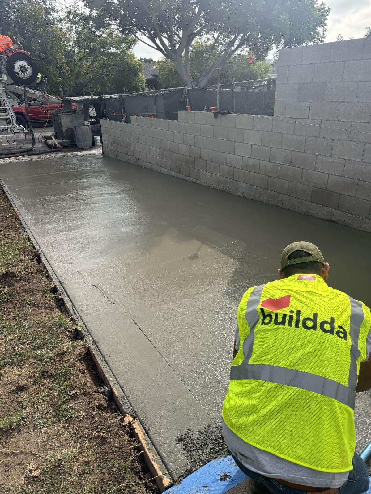 Buildda crew member floating fresh concrete along a block wall on a Santa Monica driveway