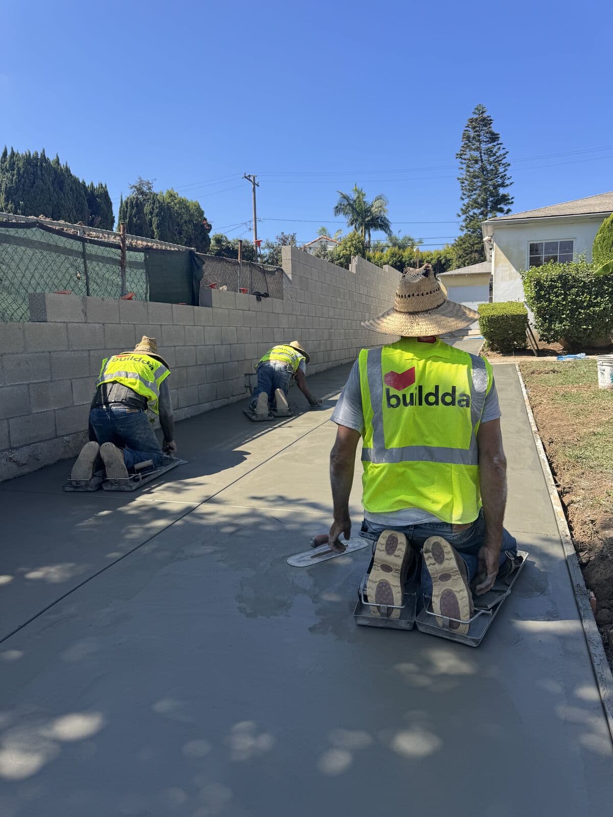 Buildda crew on kneeboards tooling control joints in a new concrete driveway in Santa Monica