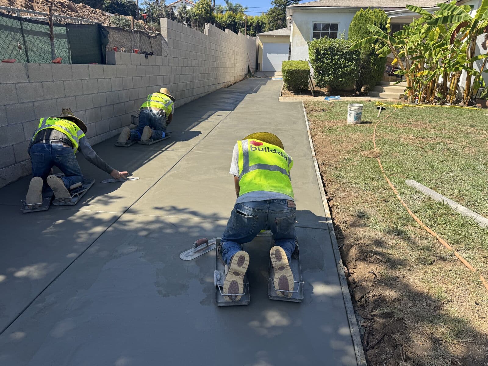 Three Buildda finishers working the full length of a new concrete driveway in Santa Monica